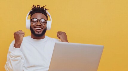 Wall Mural - a man in a yellow shirt is wearing headphones and smiling while using a laptop. concept of happiness