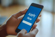© Ram - Hands holding a smartphone displaying 'Apply Now' on a blue screen, representing quick online applications, career opportunities, and the convenience of mobile job searching