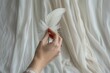 © Konstiantyn Zap - Close-up of female hand holding white feather against soft fabric background