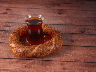 Simit and tea, delicious Turkish traditional cuisine bakery product simit and tea over wooden table. Black and brown background, copy space. Fresh baked round bagel with sesame seeds.