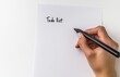© Kien - A woman's hand holding a pen and writing on a white paper with the text 'to-do list' in the center of the page