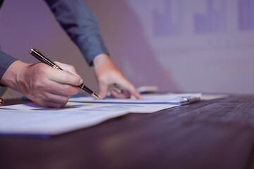 Wall Mural - A close-up of a male businessman at his desk, analyzing overtime graphs and business charts in a finance office at night. He checks data meticulously to make critical decisions