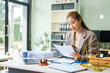 © NanSan - A young female lawyer sits at her desk in the office, providing online legal advice professionally. Legal documents, a computer, a judge's gavel, and scales symbolize justice and law