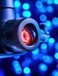 © Vee - Close-up of Camera Lens with Red Light and Blue Bokeh Background