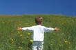 © Thanyarat - A joyful child running through a meadow with arms outstretched, the sun shining and grass swaying gently