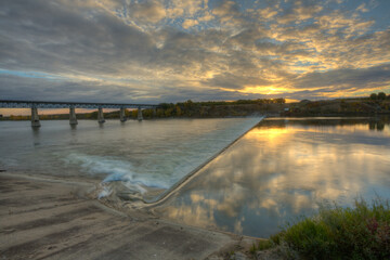 Wall Mural - a bridge spans a river with a beautiful sunset in the background