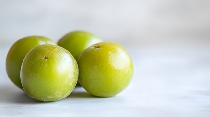 Wall Mural - Green plums rest on a light gray surface