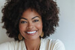 © hkjdesign - A portrait of a smiling Black woman with an afro hairstyle  wearing gold earrings and a white shirt.