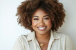 © hkjdesign - A smiling Black woman with a big afro  wearing a beige shirt and gold jewelry.