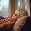 © Serhii - Blonde-Haired Boy Enjoying a Peaceful Nap in a Sunlit Window Seat on a Cozy Day