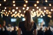 © YouraPechkin - Woman standing with her back to a festive gathering illuminated by string lights