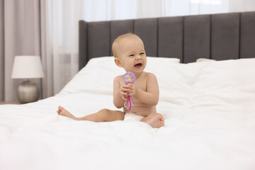 Wall Mural - Cute little baby with rattle on bed indoors