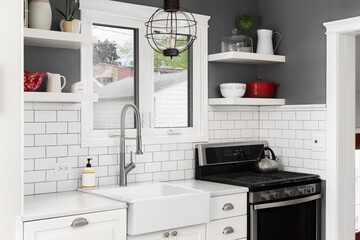 Wall Mural - A kitchen faucet detail with white cabinets, farmhouse sink in front of a window, floating shelves on a dark grey wall, and a white subway tile backsplash.