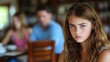 © Neural Pixels - A teenage girl sits quietly in a cafe, appearing thoughtful as family members chat in the background