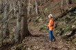© EdNurg - Woman enjoying trekking in the woods during fall season, wearing hiking boots and using poles