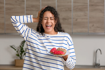 Poster - Emotional African-American woman with tasty eclairs in kitchen