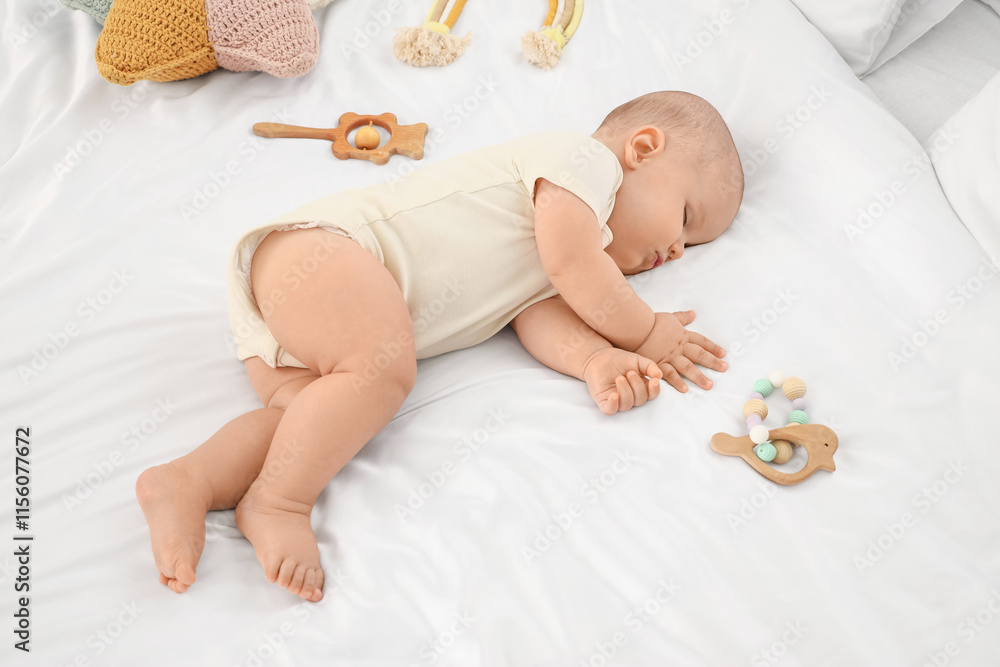 Cute little baby sleeping with toys on bed