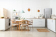 © Pixel-Shot - Blurred view of light kitchen with white counters, shelf unit and dining table