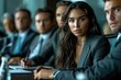 © neatlynatly - A woman in a business suit leads a focused discussion in a modern office setting, with colleagues attentively listening.