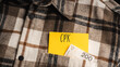 © Jakub - Yellow card with a handwritten inscription '`CPK', protruding from a brown plaid shirt, next to Polish banknotes PLN (selective focus)