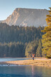© EdNurg - Woman hiker with raised arms enjoying the view of Black Lake and Durmitor massif in Montenegro