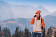 © EdNurg - Young woman hiker using smartphone on mountain top with scenic view