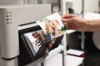 © New Africa - Woman with colorful photos near modern printer indoors, closeup