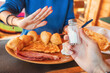 © EdNurg - Woman refusing salt shaker while having breakfast with scrambled eggs, bacon, fried dumplings and cheese, in restaurant