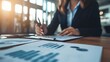 © Thuntaree - Businesswoman Analyzing Reports and Charts in Modern Office Setting