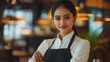 © Sabana - Young woman smiling confidently while working in a modern restaurant setting.
