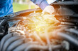 © sorapop - Professional mechanic examining car coolant level and performing maintenance. Expert checking engine liquid by opening tank cap with men's hand is visible.