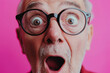 © lashkhidzetim - man with glasses is looking surprised. The image has a pink background. The man's expression is intense and his eyes are wide open