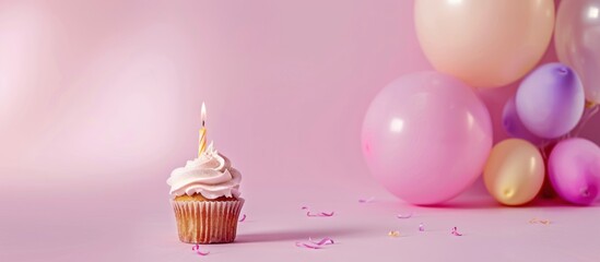 Wall Mural - Birthday cupcake with candle and pastel balloons on pink background.