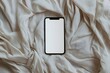 © CamThali - Photo of a blank white screen on a smartphone lying flat on a bed, with the phone covered by fabric