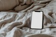 © CamThali - Photo of a blank white screen on a smartphone lying flat on a bed, with the phone covered by fabric