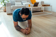 © simona - A mature man aged fifty practicing a plank on the wooden floor of his apartment, focusing on building core strength, improving endurance, and maintaining a health-conscious fitness routine wellness