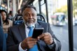 © Milos - A confident middle-aged man in business attire sits on a bus, focused on his smartphone, showcasing the modern commuter lifestyle and connectivity in urban settings.