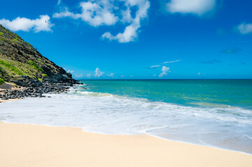 Wall Mural - beach with a rocky shoreline and a small hut in the distance