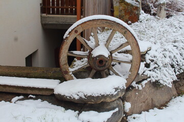primo piano di una ruota di carro ricoperta dalla neve utilizzata come ornamento per una casa di mon