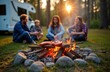 © Pete - Family enjoys outdoor cooking session by bonfire. Happy family with motorhome. They sit around campfire in forest. They prepare sausages. It is a summer evening. They enjoy leisure time.