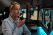 © pressmaster - Young blond female officer of surveillance room reporting situation on walkie-talkie while looking at desktop computer screen