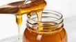 © Natsumae - Golden honey pours smoothly from a wooden spoon into a glass jar, a delicious, natural sweetness.