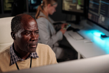 serious experienced it engineer looking at desktop computer screen while decoding online data or dev