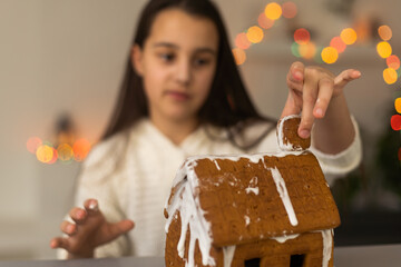 Cute little girl with gingerbread spooky house with festive icing and ghost shaped cookie. Happy Halloween