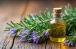 © miss irine - Rosemary essential oil in glass bottle sits on rustic wooden surface surrounded by sprigs of fresh rosemary with purple flowers. Natural aroma therapy product. Healthy herbal extract. Natural organic