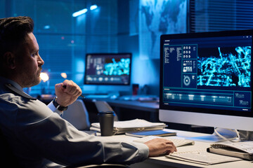 Aufkleber - Young serious male operator in uniform looking at graphic data on computer screen while sitting by workplace