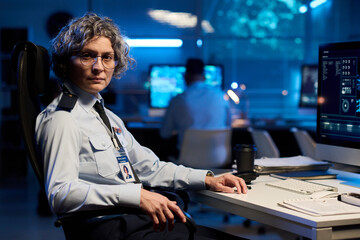 Aufkleber - Experienced female officer in eyeglasses and uniform looking at camera while sitting by desk with computer monitor