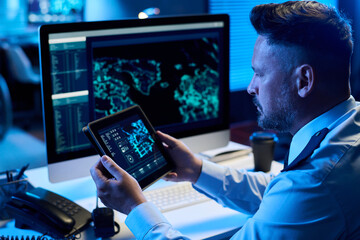 Aufkleber - Serious mature man in uniform sitting by workplace in military command center and learning graphic data on tablet screen