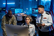 © pressmaster - Team of serious workers of military command center looking at online data while sitting and standing in front of computer monitor