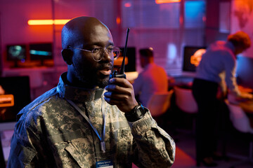 Aufkleber - Young confident African American male officer in camouflage uniform speaking in walkie-talkie in military command office